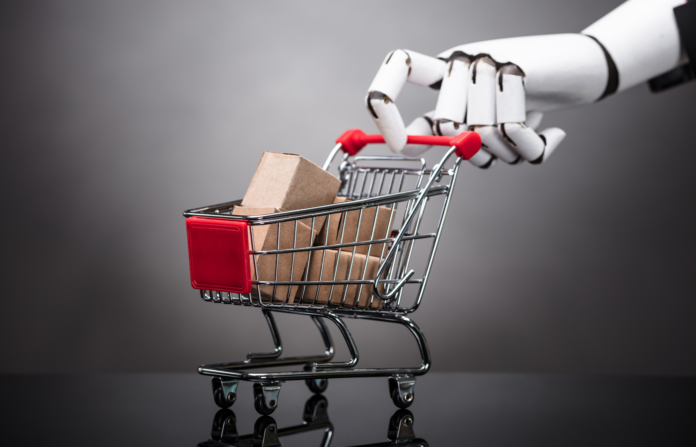 Robot holding mini shopping cart with cardboard boxes.